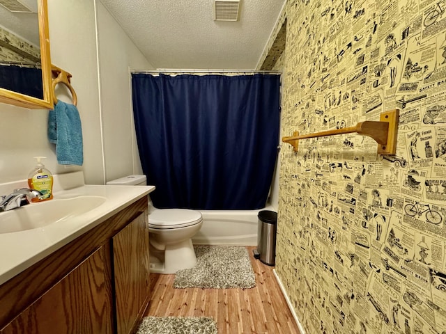 bathroom featuring a textured ceiling, wood finished floors, toilet, vanity, and shower / tub combo with curtain