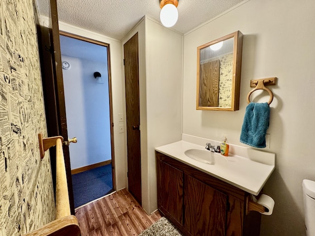 bathroom featuring wood finished floors, a textured ceiling, toilet, and vanity