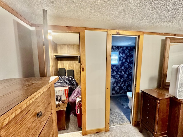 carpeted bedroom with a textured ceiling and wallpapered walls