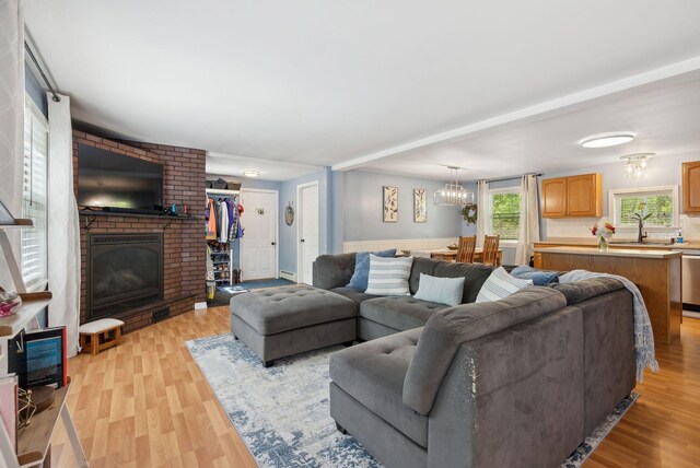 65 Lone Indian Trl, Augusta, ME 04330 - living room with light wood-style flooring, a brick fireplace, and a chandelier