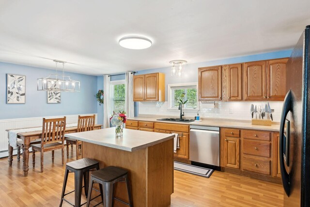 65 Lone Indian Trl, Augusta, ME 04330 - kitchen featuring stainless steel dishwasher, a sink, freestanding refrigerator, a breakfast bar, and light wood-style floors