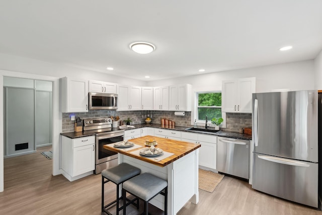 510 Minot Ave, Auburn, ME 04210 - kitchen with stainless steel appliances, a kitchen bar, tasteful backsplash, light wood-type flooring, and white cabinetry