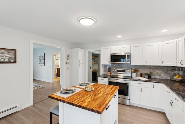510 Minot Ave, Auburn, ME 04210 - kitchen with stainless steel appliances, baseboard heating, wooden counters, a kitchen bar, and tasteful backsplash