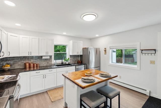 510 Minot Ave, Auburn, ME 04210 - kitchen featuring a baseboard radiator, stainless steel appliances, a sink, a breakfast bar area, and light wood-style flooring