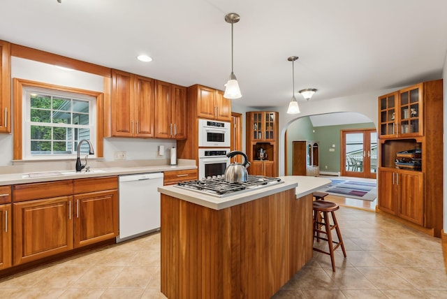 1 Whispering Pines Dr, Old Orchard Beach, ME 04064 - kitchen with white appliances, arched walkways, brown cabinetry, glass insert cabinets, and light countertops