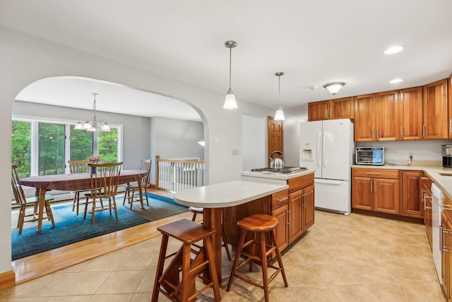 1 Whispering Pines Dr, Old Orchard Beach, ME 04064 - kitchen with white refrigerator with ice dispenser, arched walkways, brown cabinets, light tile patterned floors, and a kitchen island