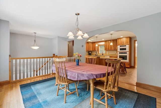 1 Whispering Pines Dr, Old Orchard Beach, ME 04064 - dining space with light wood-type flooring, arched walkways, baseboards, and a chandelier