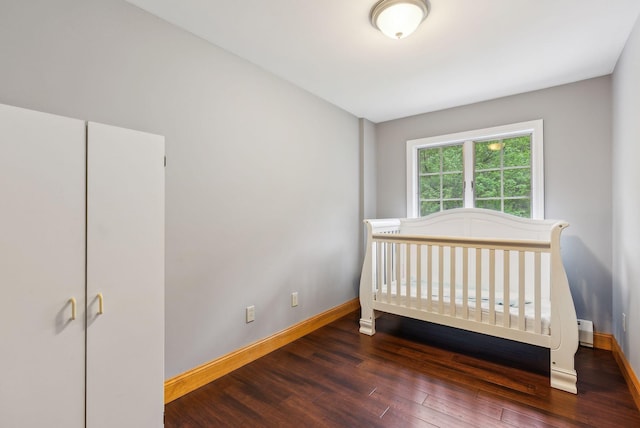 1 Whispering Pines Dr, Old Orchard Beach, ME 04064 - unfurnished bedroom featuring baseboards, wood finished floors, baseboard heating, and a crib