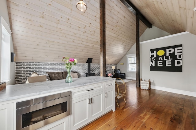 16 Cross St, Camden, ME 04843 - kitchen with a wood stove, light wood-style floors, stainless steel microwave, baseboards, and white cabinets