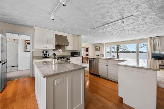 21 Ledge Rd, Cumberland, ME 04110 - kitchen featuring stainless steel appliances, wall chimney exhaust hood, a sink, a large island with sink, and light wood-type flooring