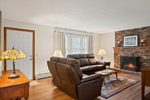 12 Friar Tuck Ln, Brewer, ME 04412 - living room featuring a baseboard heating unit, light wood-style flooring, a brick fireplace, and a textured ceiling