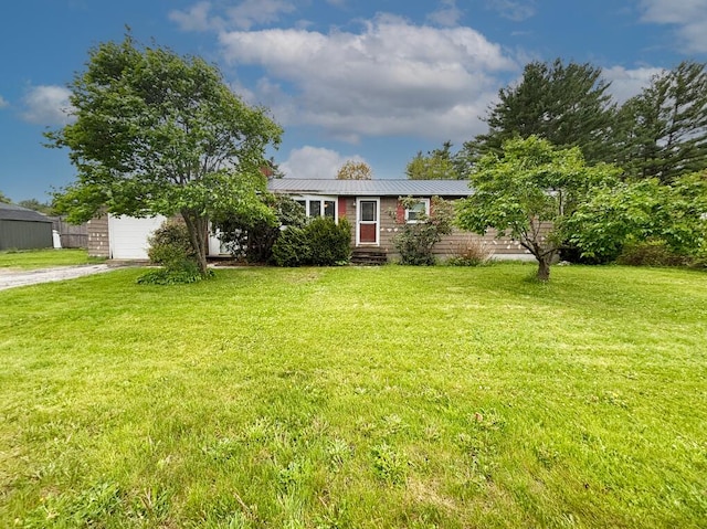view of front of home featuring driveway, a front yard, an attached garage, metal roof, and entry steps