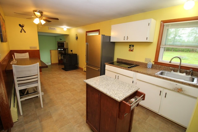 kitchen with freestanding refrigerator, a sink, ceiling fan, white cabinets, and black electric cooktop