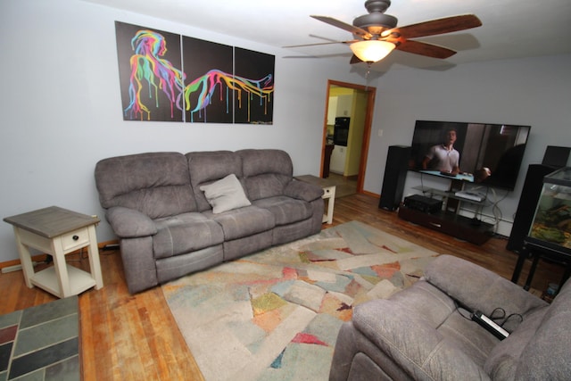 living area with wood finished floors, a ceiling fan, and baseboards