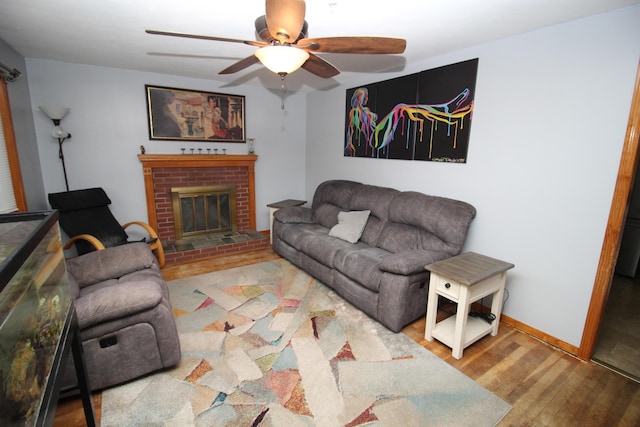 living room featuring ceiling fan, wood finished floors, a fireplace, and baseboards