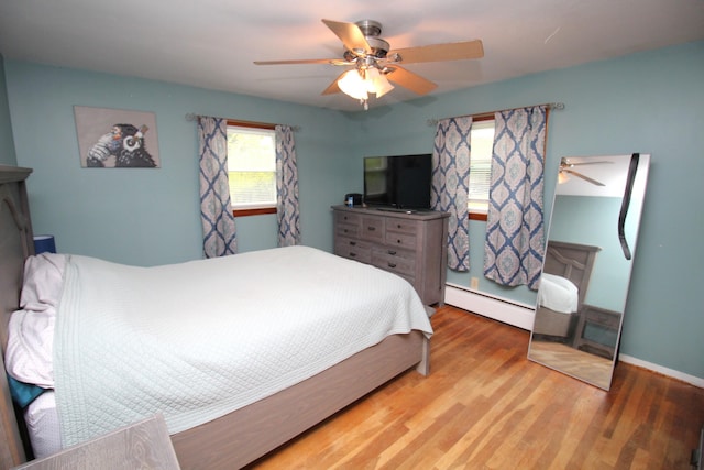 bedroom with baseboard heating, wood finished floors, ceiling fan, and baseboards