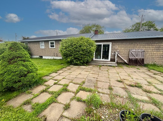 back of property featuring a chimney, metal roof, and a patio