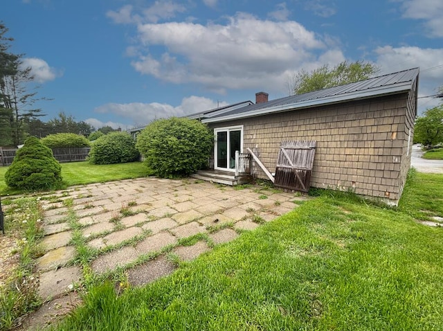 back of property with a yard, a patio area, a chimney, and metal roof