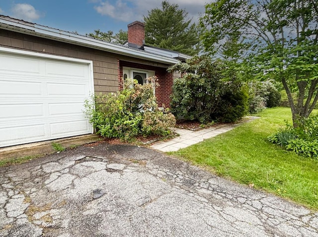 view of home's exterior featuring a chimney, a yard, and a garage