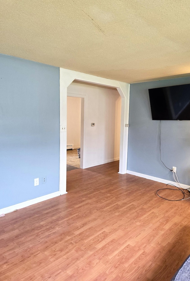 25 Mill Ln, Naples, ME 04055 - empty room with arched walkways, wood finished floors, a textured ceiling, and baseboards