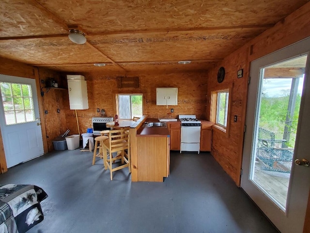 259-265 Bowden Point Rd, Prospect, ME 04981 - kitchen with white gas stove, concrete flooring, light countertops, a peninsula, and a breakfast bar
