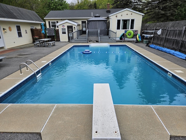 view of pool featuring a gazebo, an outdoor structure, a patio area, a diving board, and a wooden deck