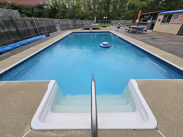view of pool with a patio, a fenced backyard, and view of wooded area