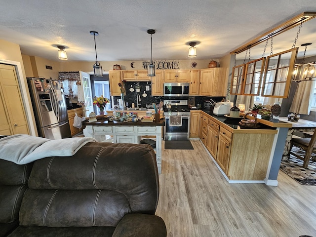 kitchen featuring stainless steel appliances, dark countertops, plenty of natural light, light wood-style flooring, and a textured ceiling