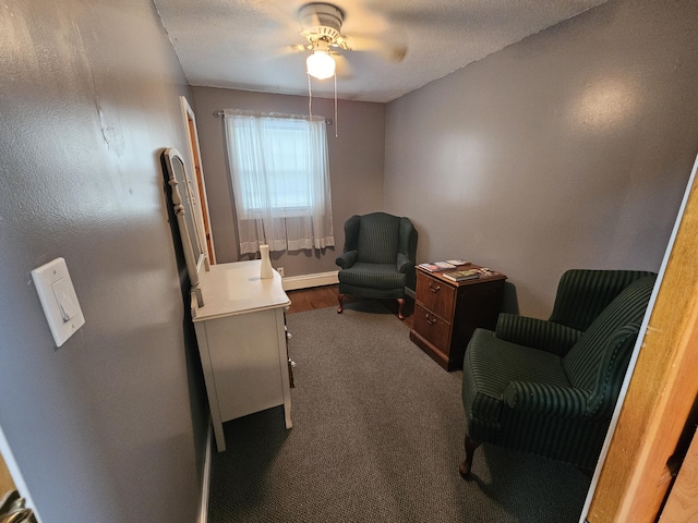 living area with ceiling fan and dark colored carpet