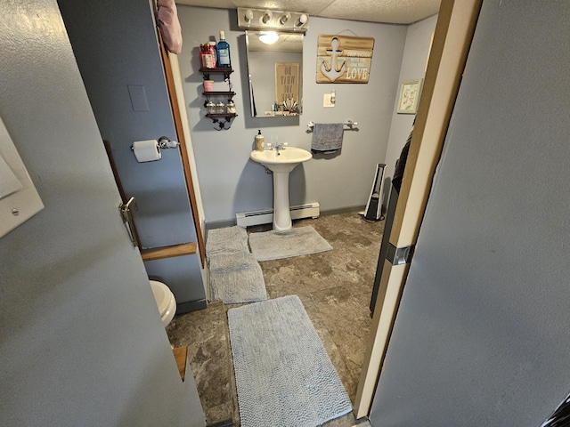 bathroom featuring baseboard heating, toilet, and baseboards