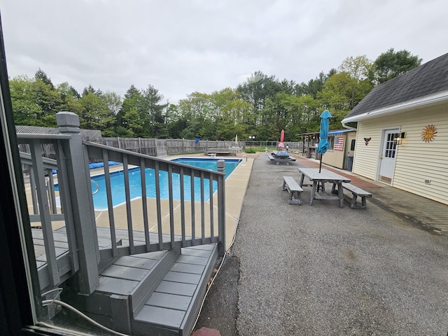 view of swimming pool with a fenced backyard, view of scattered trees, a patio, and outdoor dining space