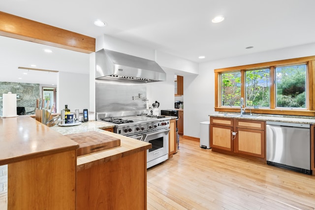 21 Harpswell Islands Rd, Harpswell, ME 04079 - kitchen with stainless steel appliances, wall chimney range hood, a sink, a peninsula, and light wood-style floors