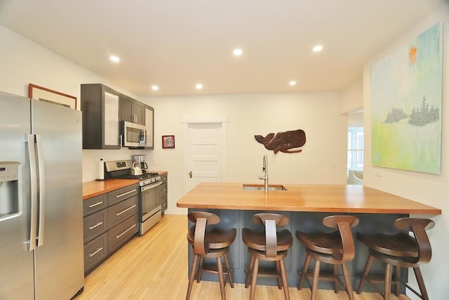 228 French St, Bangor, ME 04401 - kitchen with appliances with stainless steel finishes, a sink, a breakfast bar area, butcher block counters, and recessed lighting