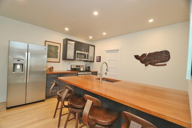 228 French St, Bangor, ME 04401 - kitchen featuring stainless steel appliances, a sink, wooden counters, a kitchen breakfast bar, and light wood finished floors