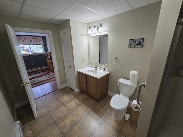 101 Streamside Ln Unit 21, Bangor, ME 04401 - bathroom featuring a baseboard heating unit, toilet, a paneled ceiling, vanity, and baseboards
