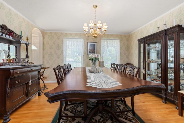 31 Rebecca Rd, Ogunquit, ME 03907 - dining room with wallpapered walls, light wood finished floors, a chandelier, arched walkways, and crown molding