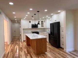 12 Windsor Rd, Ellsworth, ME 04605 - kitchen featuring freestanding refrigerator, a kitchen island, light wood finished floors, light countertops, and white cabinetry