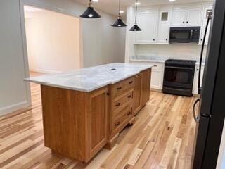 12 Windsor Rd, Ellsworth, ME 04605 - kitchen with black appliances, white cabinets, light wood-type flooring, light countertops, and a center island