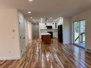 12 Windsor Rd, Ellsworth, ME 04605 - kitchen featuring a kitchen island, baseboards, white cabinets, open floor plan, and wood finished floors