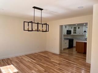 12 Windsor Rd, Ellsworth, ME 04605 - unfurnished dining area featuring wood finished floors, baseboards, and a chandelier