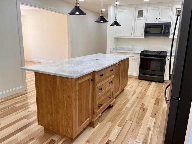 12 Windsor Rd, Ellsworth, ME 04605 - kitchen featuring black appliances, light wood-style floors, light stone counters, a center island, and white cabinets