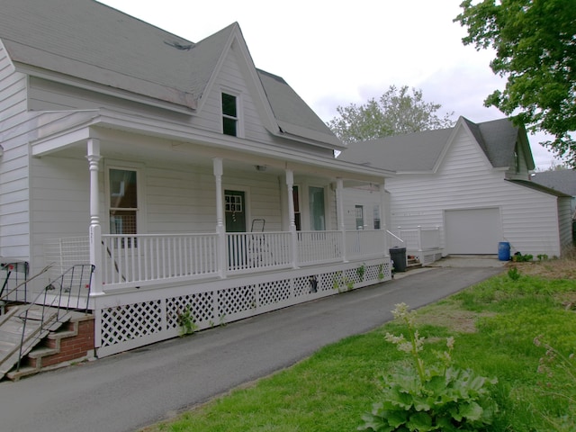 country-style home with covered porch, a garage, and driveway