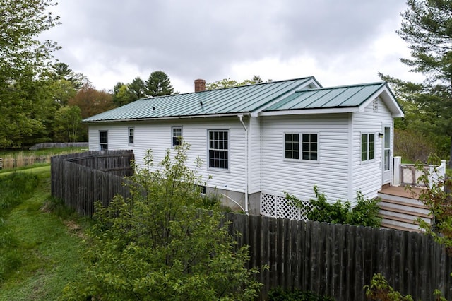 31 Lakeview Dr, West Bath, ME 04530 - view of home's exterior with a chimney, a fenced backyard, a deck, metal roof, and a standing seam roof