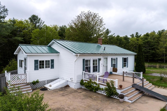 31 Lakeview Dr, West Bath, ME 04530 - view of front facade featuring a chimney, a wooden deck, a patio, metal roof, and a forest view