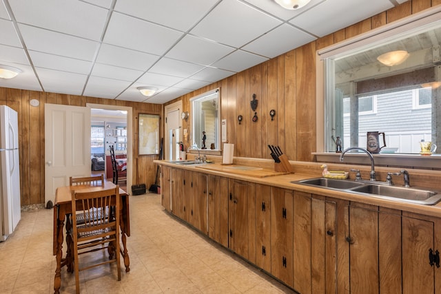 27 Ocean Ave Extension Unit 2, York, ME 03909 - kitchen with a sink, wood walls, freestanding refrigerator, brown cabinetry, and light countertops