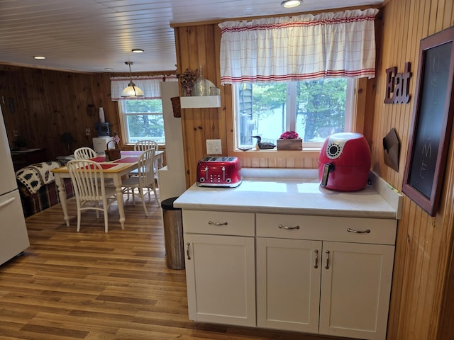 101 Brooks & Dunn Road, Otis, ME 04605 - kitchen featuring wooden walls, white cabinets, light countertops, wood finished floors, and freestanding refrigerator