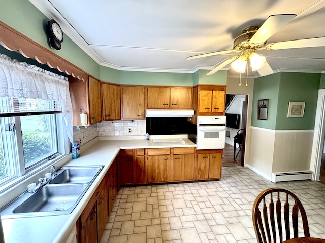 187 Maine Ave, Millinocket, ME 04462 - kitchen featuring oven, a baseboard heating unit, under cabinet range hood, brown cabinetry, and crown molding