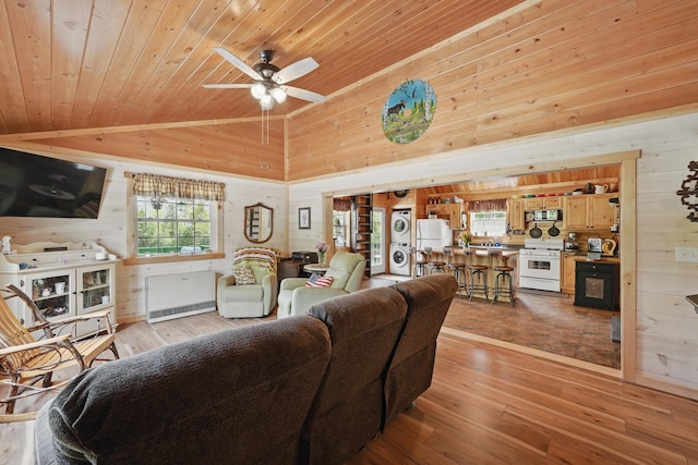 30 Bassett Ln, Moscow, ME 04920 - living room featuring wooden walls, stacked washing machine and dryer, wooden ceiling, light wood finished floors, and a ceiling fan