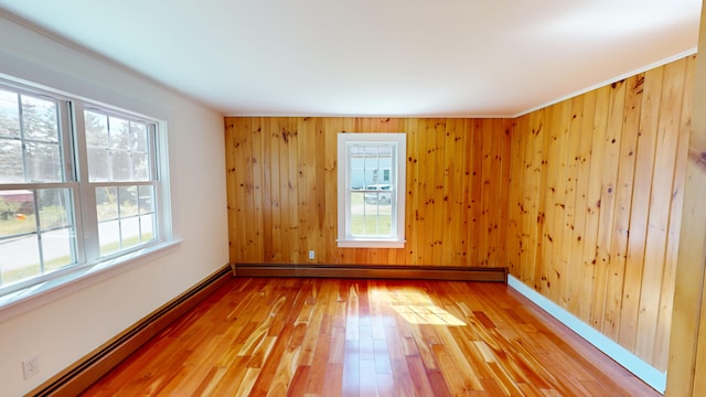 103 Water St, Machias, ME 04654 - empty room featuring a baseboard radiator, healthy amount of natural light, hardwood / wood-style floors, baseboards, and wooden walls