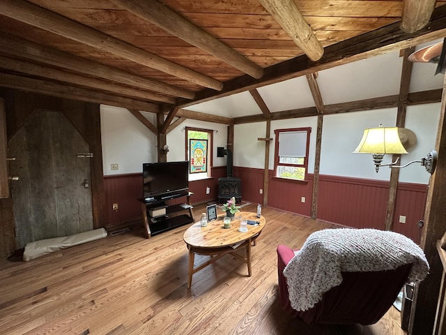 217 Jackson Rd, Monroe, ME 04951 - living room featuring wainscoting, a wood stove, light wood-style floors, wooden walls, and wood ceiling with exposed beams